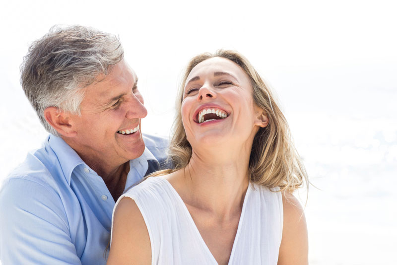 dental implant patients smiling and laughing with new permanent implants