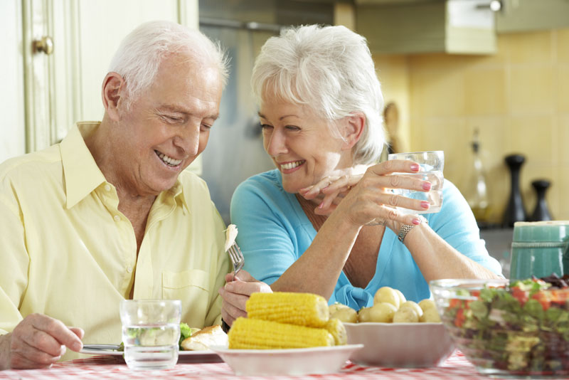 A couple smiling at each other over the breakfast table because they have been treated with advanced dental implant technology